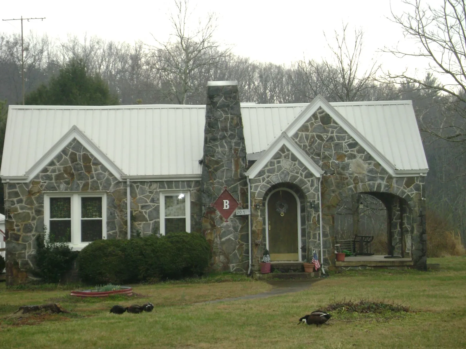 White metal roof on a stone cottage with steep gables in Lahoma