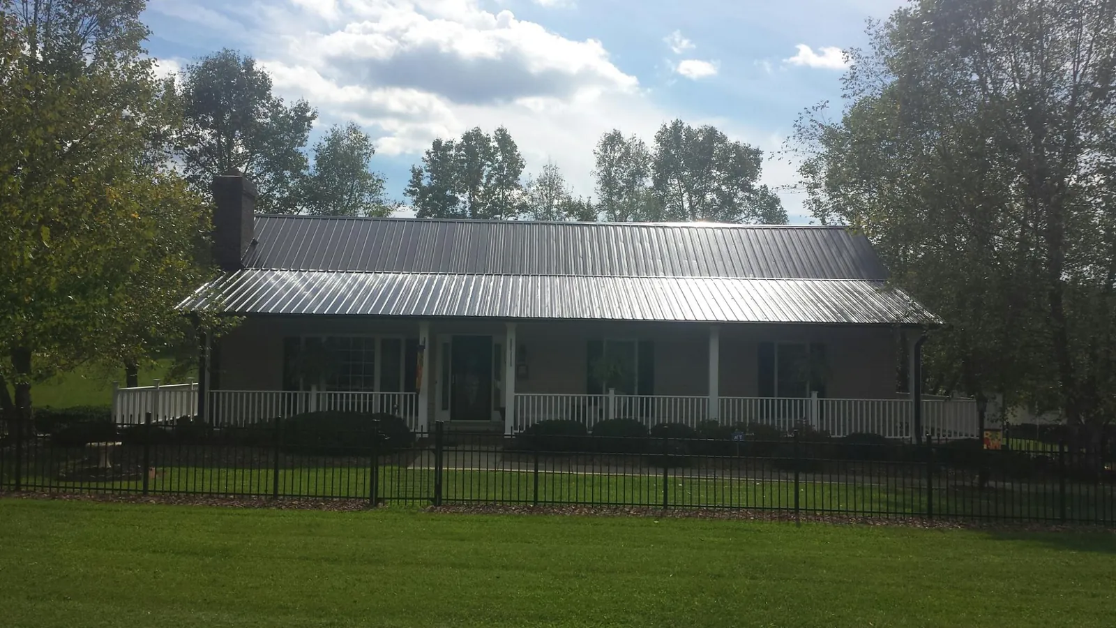 Gray metal roof on a brick ranch with a full width front porch — Gutter Guard Installation work by our crew in Lahoma