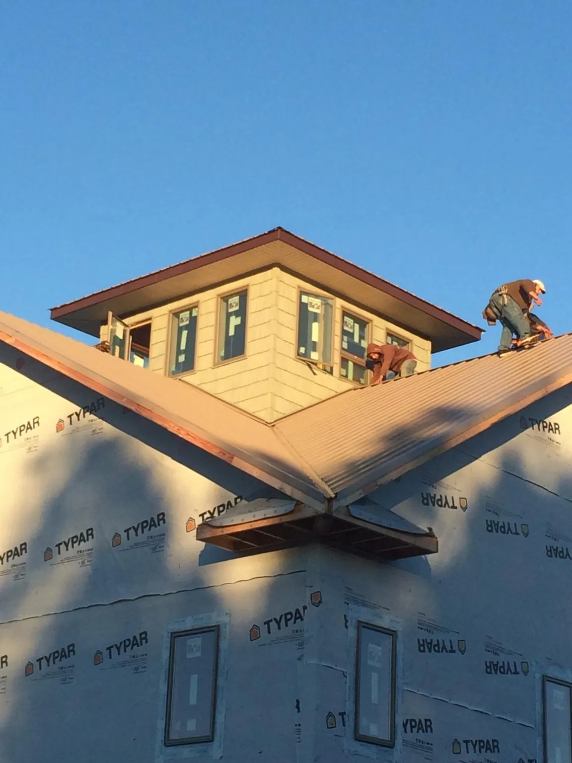 Roofers working around a rooftop cupola on a new metal roof at sunset — Roof Waterproofing in Lahoma by Roofing Brothers